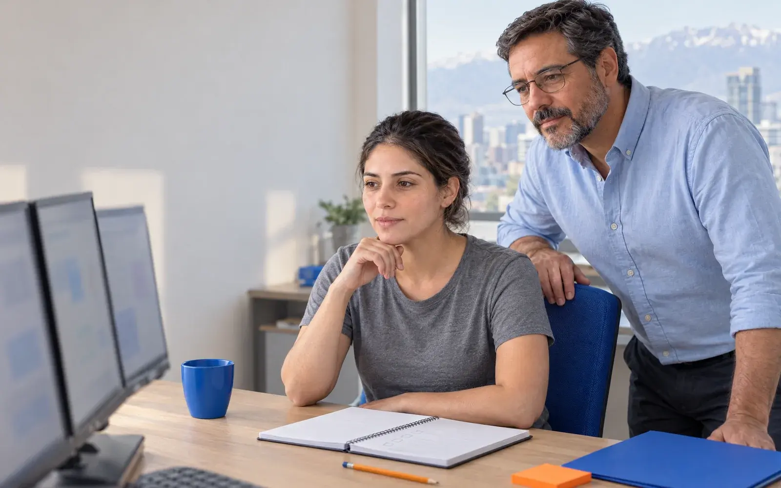 Dos personas revisan la configuración de un sistema frente a varios monitores.